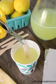 a cup filled with lemon juice and a pair of scissors