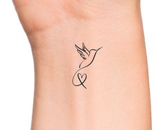 a small tattoo on the wrist of a woman's left arm with a bird flying above it