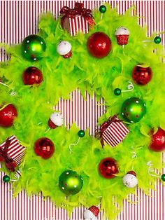 a green wreath with red and white ornaments hanging from it's sides on a striped wall