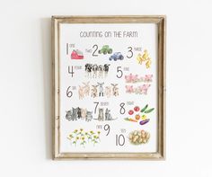 a cross stitch pattern with farm animals and flowers on it, framed in a wooden frame