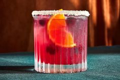 a close up of a drink in a glass with an orange slice on the rim