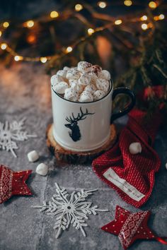 a mug filled with marshmallows sitting on top of a table next to christmas decorations