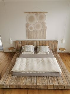 a bed made out of pallet wood in a room with wooden flooring and white walls