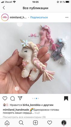 someone is holding two small stuffed animals in their hand, one has a pink and white pony on it's head