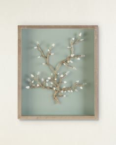 a branch with white flowers is mounted in a wooden frame on the wall above a shelf