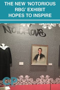 an exhibit with black and white wallpaper, clothes on mannequins and a portrait of a man