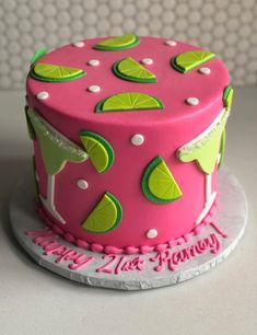 a pink cake with limes on it sitting on top of a white countertop