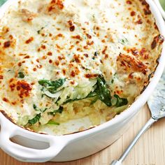 a casserole dish with cheese and spinach in it on a wooden table