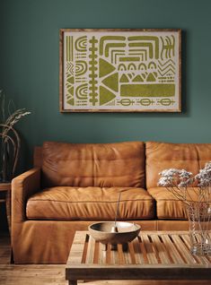 a brown leather couch sitting in a living room next to a wooden table with vases on it