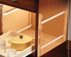 a kitchen cabinet with an open drawer and pan on the bottom shelf next to it