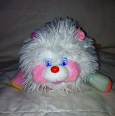 a white stuffed animal with pink and blue eyes