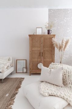 a living room filled with furniture and pillows on top of a white floor next to a wooden cabinet