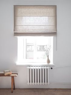 a white room with a window, radiator and wooden table in front of it