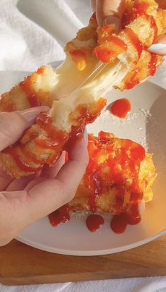 a person is eating some food on a white plate with ketchup and cheese