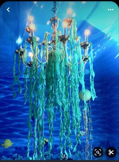 a chandelier hanging from the ceiling in front of a blue wall with fish and bubbles