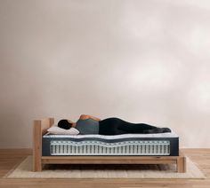 a woman laying on top of a bed in a room next to a white wall