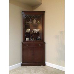 a wooden china cabinet sitting in the corner of a room