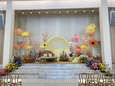 the stage is decorated with flowers and chairs