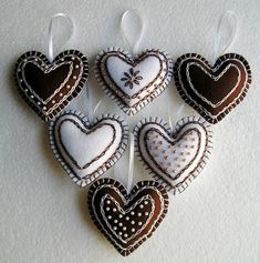 four heart shaped cookies hanging from strings on a white tablecloth background, decorated with brown and white hearts