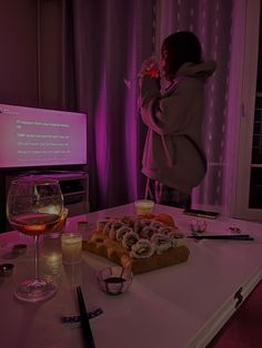 a person standing in front of a table with food and drinks on it, next to a projection screen