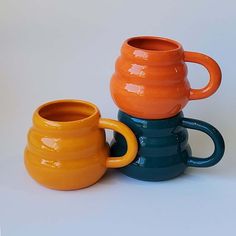 three different colored mugs sitting next to each other