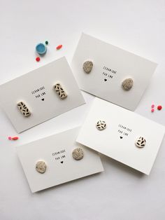 three pairs of earrings are sitting on top of a white card with confetti