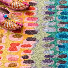 two pairs of shoes sitting on top of a colorful rug