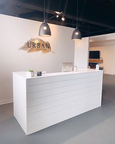 the reception desk is white and has gold lettering that reads urban on it's side