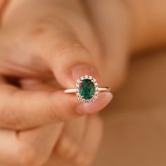 a woman holding an emerald and diamond ring