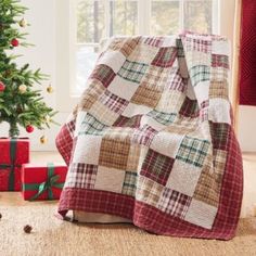 a christmas tree and presents in front of a window with a plaid blanket on it