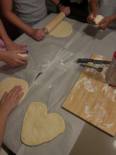 people making heart shaped pizza dough on a table