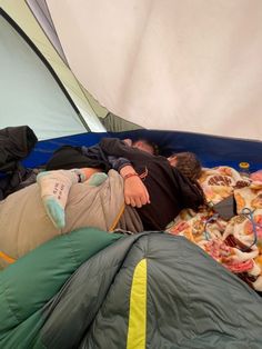 a man laying in a sleeping bag on top of a blue and green tarp