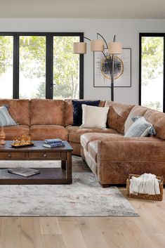 a living room filled with lots of furniture next to large windows and wooden flooring