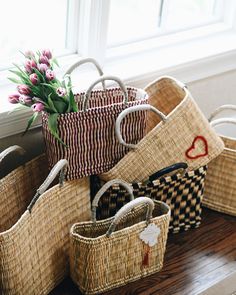 several baskets with flowers in them sitting on a wooden floor next to a window sill