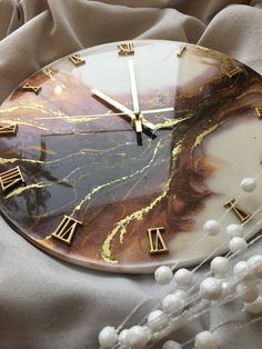 a marble clock with roman numerals on the face and gold trim around it