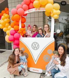 a group of people posing for a photo in front of a vw bus with balloons