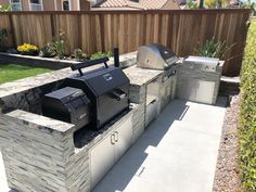 an outdoor bbq with grills and seating in the back yard