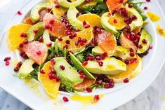 a white plate topped with sliced oranges and avocado