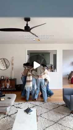 two people standing in a living room with a ceiling fan on top of the ceiling