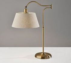 a lamp that is on top of a white table next to a gray wall and floor