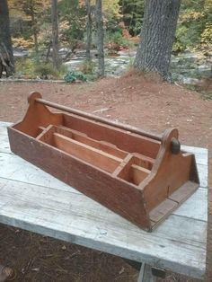 an old wooden tool box sitting on top of a table in front of some trees