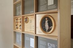 a wooden shelf with framed pictures and plaques on the wall next to it is a portrait of a woman