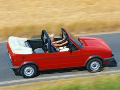 a red convertible car driving down a road