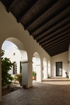 an outdoor courtyard with arches and potted plants