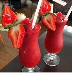 two drinks with strawberries on the rims