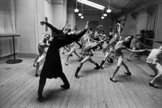 a group of people are dancing in a dance studio with their arms up and legs spread out