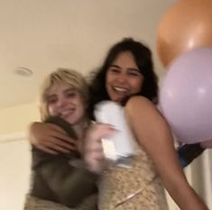 two women hugging each other with balloons in the background