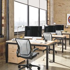 an office with two desks and three computer monitors on each side of the desk