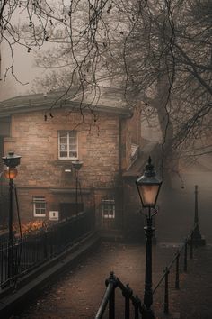 a street light sitting next to a brick building on a foggy day with trees in the background