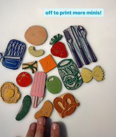 a hand is pointing at some colorful magnets on a white surface with the words, off to print more minis